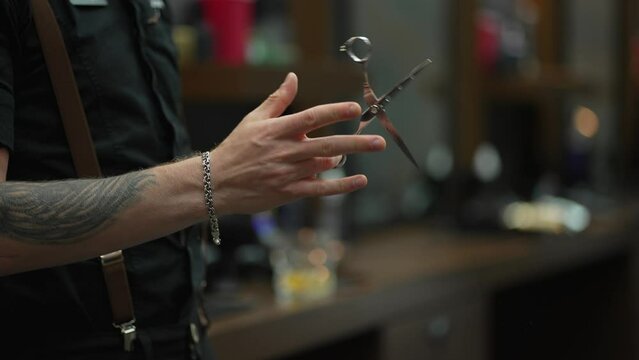 An unidentified male hairdresser twists barber scissors in his hands
