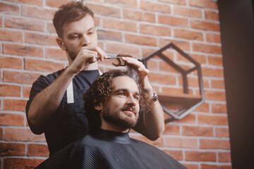 Closeup of man haircut, master does hair styling in barber shop