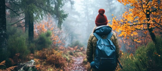 Autumn forest hike: foggy morning, woman in knit hat with backpack.