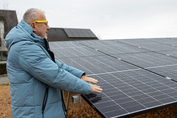 Mature man with solar power panels. Close up of mans hands above solar power panels