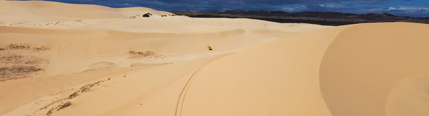Panorama offroad vehicle pickup trucks, four-wheeled motorcycle driving on large sand dunes hills at Bau Trang, Bac Binh, Binh Thuan, Vietnam, scenic desert-like landscape travel destination © trongnguyen
