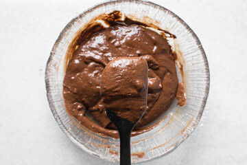 Chocolate muffin batter on a spatula, cake batter in a black spatula, the process of making chocolate muffins
