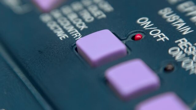 A man's finger presses the purple square button of the synthesizer, switching On-Off modes, which are confirmed by the lighting of the red LED. Closeup. Macro. Shallow depth of field. Shot in motion - Powered by Adobe