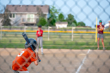 Parent view behind a chain link fence and home plate with a batter ready