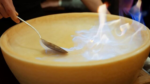 flambe cheese wheel in culinary mastery. A burst of flames enhances the decadent cheese, creating a theatrical display of gastronomic artistry presentation promises an extraordinary dining experience.