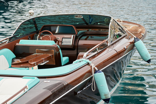 Monaco, Monte Carlo, 29 September 2022 - the wooden side of the luxury motor boat Riva in port of Hercules, sunny glare of the sun, elegance boat, glossy surfaces shine in sunny weather