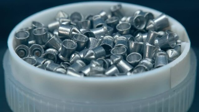 A stock of lead bullets for air guns in a white box. Closeup. Macro. Shallow depth of field. Shot in motion