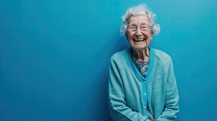 80 year old Caucasian woman with smiling happy facial expression on blue background with copy space