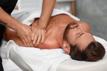 Man receiving professional massage on couch in spa salon
