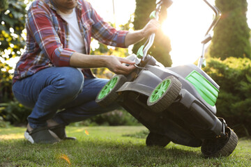 Man fixing lawn mower in garden, closeup