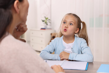 Dyslexia treatment. Speech therapist working with girl at table in room - obrazy, fototapety, plakaty