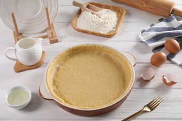 Pie tin with fresh dough and ingredients on white wooden table. Making quiche