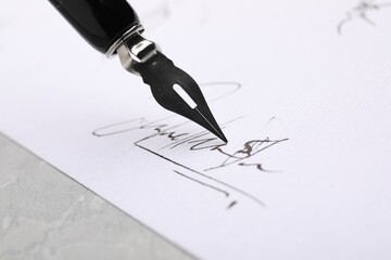 Fototapeta premium Signing on sheet of paper with fountain pen at table, closeup