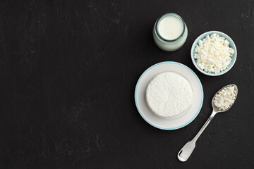 Lactose free dairy products on black textured table, flat lay. Space for text
