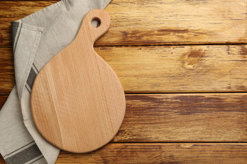 New cutting board and napkin on wooden table, top view. Space for text