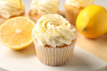 Tasty cupcake with cream, zest and lemons on board, closeup