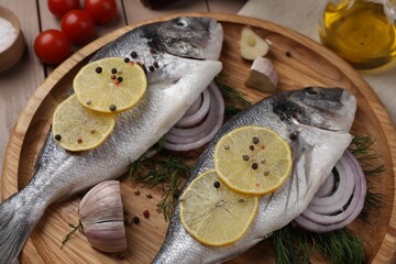 Raw dorado fish with lemon, spices and onion on table, closeup