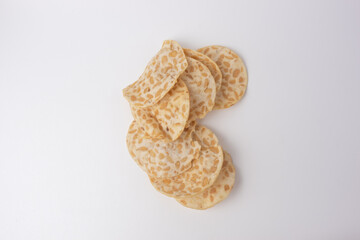 Keripik Tempe or Tempeh Chips are made from soybeans and served on a wooden plate. Isolated on white background. usually used as souvenirs