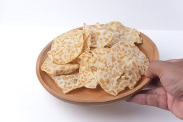 Keripik Tempe or Tempeh Chips are made from soybeans and served on a wooden plate. Isolated on...