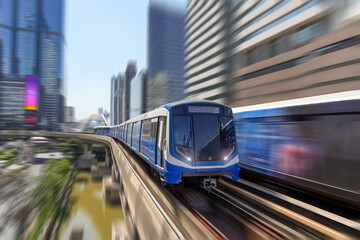 Modern high speed train over ground on a bridge on stilts among skyscrapers metro with turn speed motion blur.