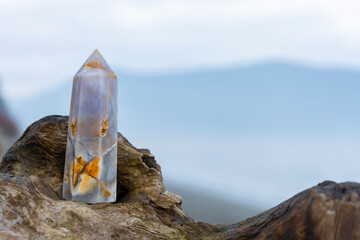 A close up image of a blue flower agate crystal with carnelian stone inclusions resting on a piece...