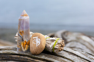 An image of a healing reiki symbol with white sage smudge stick and crystal tower on an old weathered driftwood log.  - obrazy, fototapety, plakaty