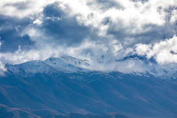 Photograph of a mountain range covered in low level grey clouds on the South Island of New Zealand