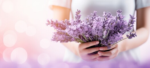 Woman holding lavender flowers with soft background. Aromatherapy and relaxation.