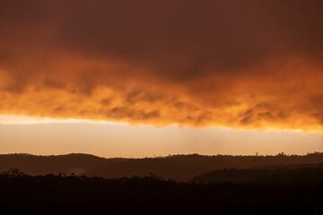 Photograph of a bright orange sunset sky over a large valley after a thunderstorm in The Blue Mountains in New South Wales in Australia