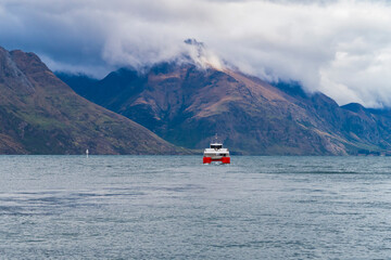 Photograph of a red and white water Ferry on Lake Wakatipu in Queenstown with mountains in the background on the South Island of New Zealand