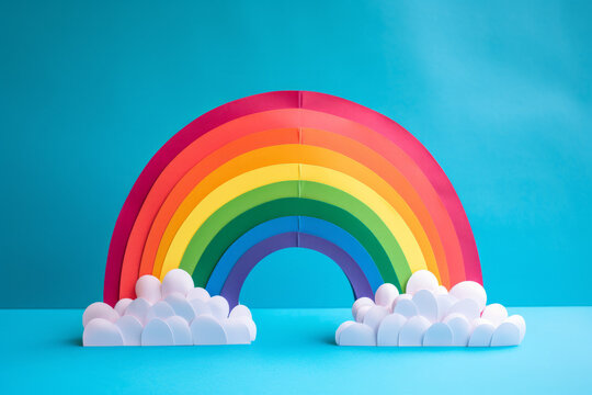 Close up photo of a papercraft rainbow, isolated on a solid blue background