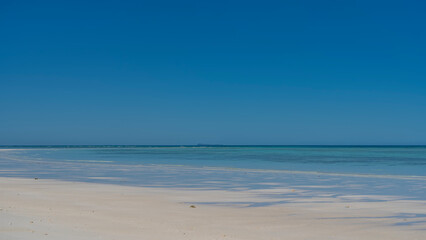 Beautiful minimalistic seascape. Endless aquamarine ocean, clear blue sky, white sandy beach. Copy Space. Madagascar. Nosy Iranja