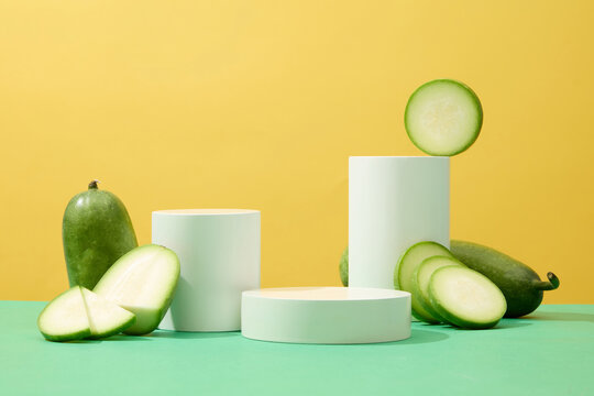 A set of round and cylinder podiums displayed with winter melon slices. Yellow background. Collection of podiums and pedestals for product presentation