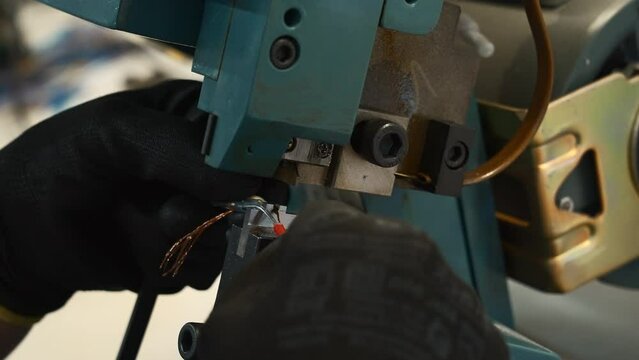 Close up of worker hands making a wire with a special machine. Creative. Industrial background at a factory workshop.