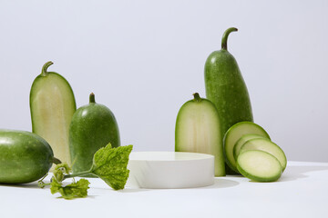 Few halves and round slices of winter melon are decorated. A podium with empty space for cosmetic product advertising. Winter melon (Benincasa hispida) is a vegetable with low carb