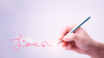 A man's hand holding a pen and writing the word love to convey pure love to a woman. Love ideas for Valentine's Day with sweet and romantic moments.