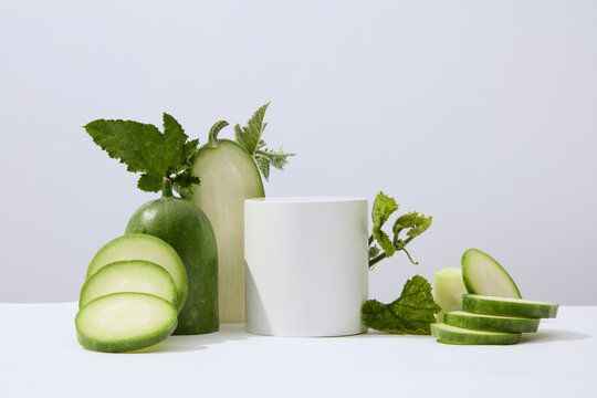 White background featured a cylinder podium white winter melon and green leaves. Studio podium or platform product template mockup of Winter melon (Benincasa hispida) extract