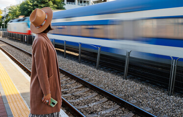 Girl at the station. A young woman in a coat and hat is standing on the station platform.