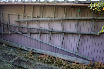 鄙びた家のトタン板の壁に掛けられた大型の古い木製の梯子