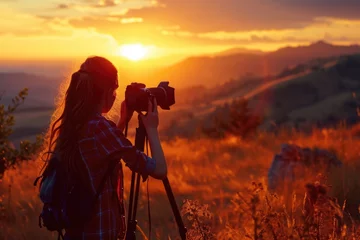 Papier Peint photo Lavable Brun A woman capturing a beautiful sunset with her camera. Perfect for travel, nature, or photography-related projects