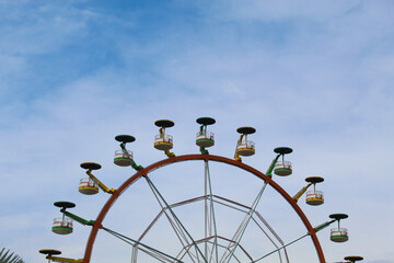Ferris wheel with cloudy blue sky background