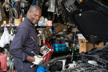 mechanic holding lug wrench for fixing a car in automobile repair shop