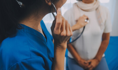 Close up of Female Doctor using stethoscope putting beat heart diagnose with patient in examination room at a hospital, check-up body, Medical and Health Care Concept. - obrazy, fototapety, plakaty