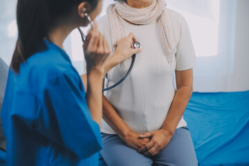 Close up of Female Doctor using stethoscope putting beat heart diagnose with patient in examination room at a hospital, check-up body, Medical and Health Care Concept.