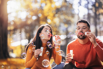 Young couple relaxing in the park with bubble blower.