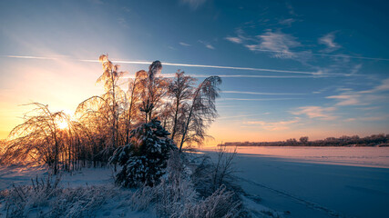 Beautiful snowy winter landscape. Winter golden sunrise on the frozen river. Golden light on snow....