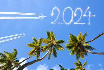Happy New Year concept. Flying airplanes and 2024 writen with sparklers on blue sky.