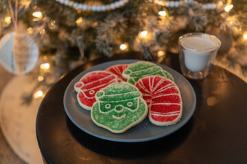Plate of holiday cookies and glass of milk for Santa in front of tree