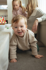 Fototapeta premium Little boy giggles with glee while decorating gingerbread house