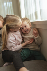Brother and sister tickle each other during festive family morning